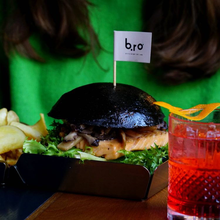 burger al carbone con salmone, patatine fritte e drink al campari con scorza di arancia.